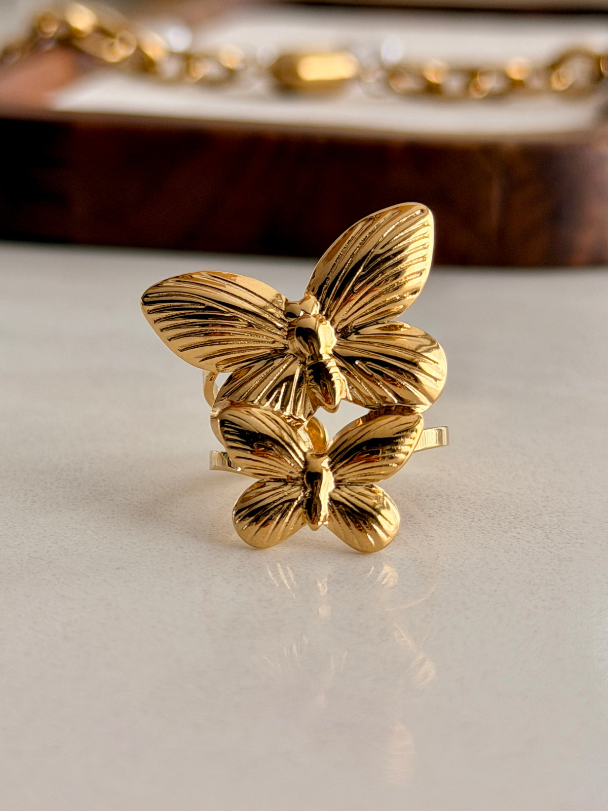 Gold butterfly-shaped ring on a light surface with a blurred background