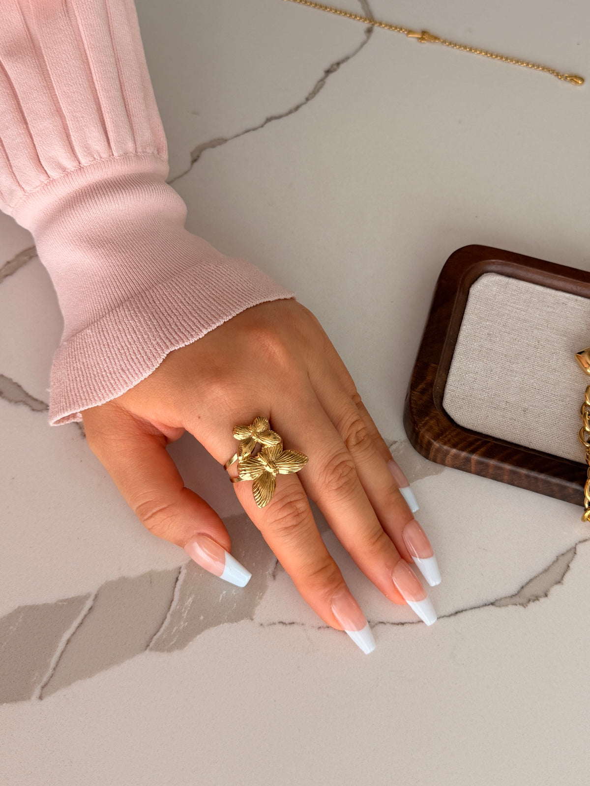 Hand wearing a gold ring on a marble surface